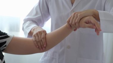 Kadın doktor eli, Asyalı hasta kadının koluna masaj yaparak fizik tedavi uyguluyor..