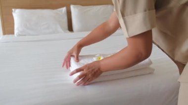Plumeria çiçeği ve havlular lüks otel odasındaki yatağın üzerinde turist seyahatine hazır ve otel hizmetçisinin elleri yatak odasını temizliyor..