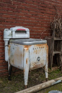 Dawsonville, Georgia USA - October 24, 2015  A vintage obsolete Maytag washer intact rusting outside against a building all complete with a motor