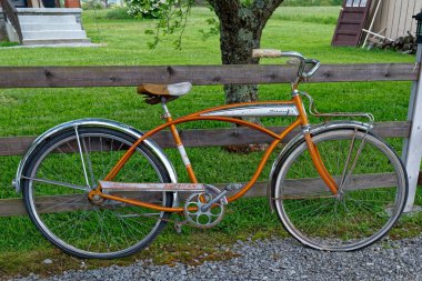 Crossville, Tennessee USA - 10 Mayıs 2023 Turuncu ve beyaz 1960 model Schwinn bisikleti tamamen paslanmamış bir çite yaslanıyor ve hala kullanılabilir yakın çekim görüntüsü takınıyor
