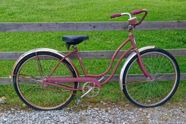 Crossville, Tennessee USA - 10 Mayıs 2023 Bir kız Schwinn 1960 'ların retro bisikleti Hollywood modeli çitlere yaslanıyor ve biraz pas ve soluk boyayla çalışıyor.
