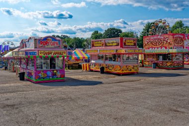 Cookeville, Tennessee USA - August 09, 2024  Variety of food trailers at a carnival at the fair all set up ready to go bright and colorful attractions with the rides in the background on a sunny day in summertime clipart