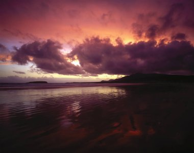 Sahilde dramatik bulutlarla muhteşem bir gün batımı.