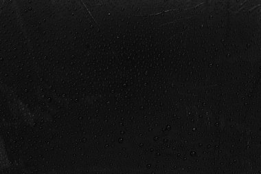 Siyah plastik zemin üzerinde su damlacıkları.