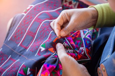 Turuncu iplikle süsleme yapan bir kadının elleri..