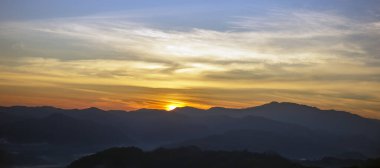 Ufukta güneş batıyor ve büyük, güzel dağlar var..