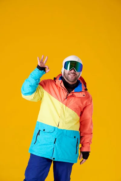 Uśmiechnięty Mężczyzna Goglach Odzieży Snowboardowej Robi Podniesioną Ręką Żółtym Tle — Zdjęcie stockowe