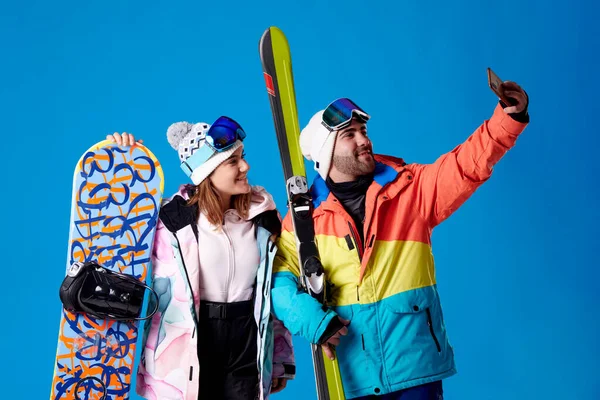 스키와 스노보드를 남녀가 배경에 웃으면서 셀카를 — 스톡 사진
