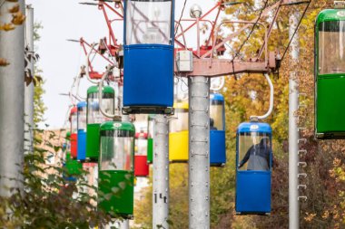 Kharkiv şehrinde sonbaharda altın ağaçlar ve gri gökyüzü olan renkli kablo nakliye kulübeleri