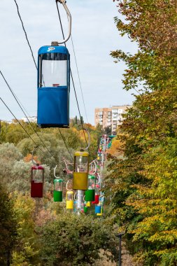 Kharkiv şehir eğlence parkında sonbahar ağaçlarıyla dolu renkli kablo taşıma kulübeleri