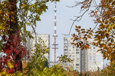 Ukrayna 'nın başkenti Kharkiv' de sonbaharda çok katlı binalar arasında mavi gökyüzünde bulunan telekomünikasyon kulesi antenleri.