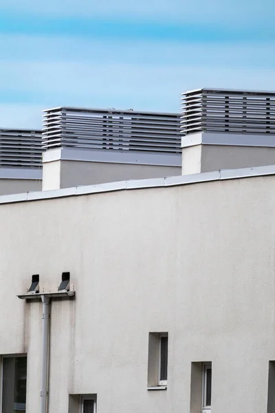 House outdoor roof ventilation units on white walls on sky background. Air conditioner system set on building roof. Architecture elements close-up