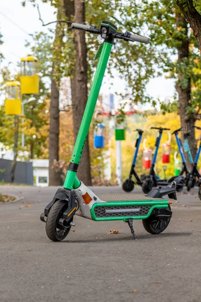カラフルなロープウェイキャビンと秋の公園でアスファルトの道路に立って電動スクーター ブルーバックでハリコフ市のレクリエーション公園の公共の電子スクーターの駐車場 — ストック写真