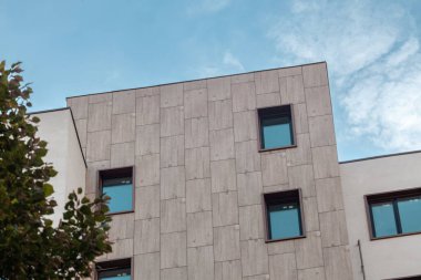 Modern bina dış mimarisi detayları. Döşeme ve beyaz duvarlar, gökyüzünde mavi pencereler, emlak dış tasarım elementleri.