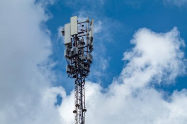 Bulutlardaki mobil telekomünikasyon kulesi, antenli baz istasyonu ve elektronik iletişim cihazları.
