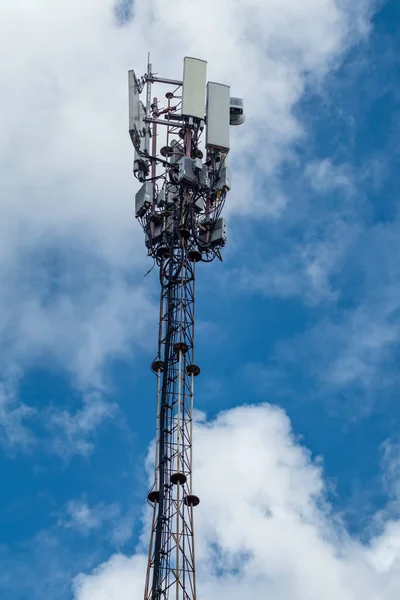 Mobile telecommunication tower with antennae and electronic communications equipments on blue sky with clouds