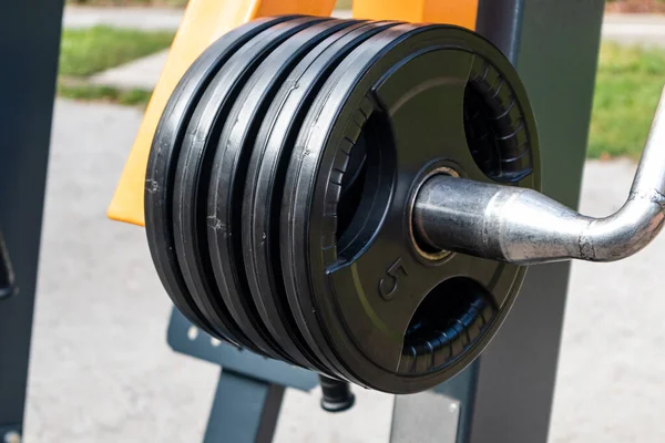 Outdoor sports ground with weight training equipment. Five kilo weights close-up