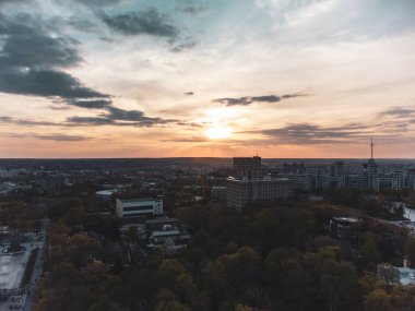 Harkiv kenti Shevchenko parkı, Derzhprom ve Karazin Ulusal Üniversitesi binaları üzerinde günbatımı şehir hava manzarası Ukrayna 'nın Kharkiv kentindeki destansı altın bulutlu binalar
