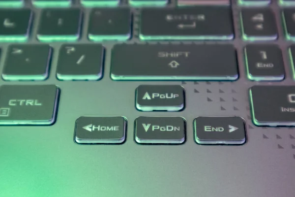 緑の光とぼやけた背景を持つノートパソコンの矢印キー 強力なグレーのノートブックキーボードのクローズアップゲーム エレクトロニクス コンピュータサイエンスの背景 — ストック写真