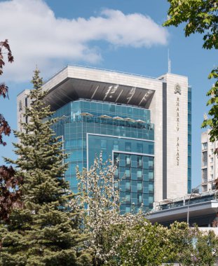 Ukrayna 'nın başkenti Kharkiv' deki Freedom Meydanı 'nda, ilkbahar yeşilliğinde modern, mavi camdan bir otel binası. Seyahat eğlencesi mimarisi