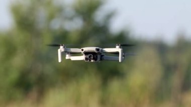 Kharkiv, Ukrayna - 02 Temmuz 2021: Dji Mini 2 İHA, yeşil yaz doğasında uçuyor. Bulanık yeşillik arkaplanı olan dört kopter aygıtı