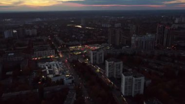 Hava geriye doğru uçuyor. Karanlık gün batımı şehri aşağıya bakıyor. Yerleşim bölgesi, çok katlı binalar, karanlık bulutlu gökyüzü. Kharkiv, Ukrayna