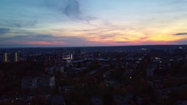 Gün batımında sokakları aydınlatan bir hava şehri. Kharkiv şehir parkı, yerleşim bölgesi binaları ve akşam üstü giden arabalar.