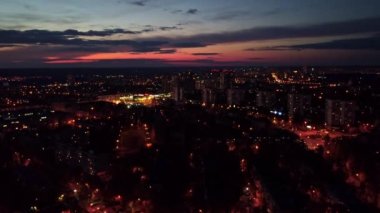 Hava kararmış gün batımı şehir manzarası. Yerleşim bölgesi, çok katlı binalar, karanlık bulutlu gökyüzü. Sağı sola kaydır
