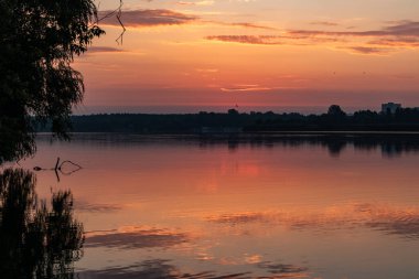 Gölde gün doğumu gökyüzü sakin ayna su yüzeyine yansıyan bulutlarla. Nehir kenarında renkli bir sabah