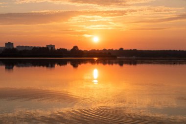 Gölde parlayan güneş ışığı sakin ayna su yüzeyine yansıyan bulutlar. Nehir kenarında renkli bir sabah