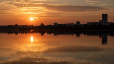 Gölde parlayan güneş ışığı sakin ayna su yüzeyine yansıyan bulutlar. Şehir parkında güneşli bir sabah