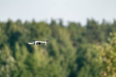 Kharkiv, Ukrayna - 02 Temmuz 2021: Dji Mini 2 İHA, yeşil yaz ormanlarında uçuyor. Çeyrek helikopter aygıtı bulanık ağaçlar ve yeşillik arkaplanı üzerinde gezinir