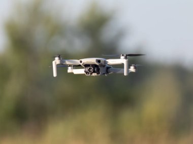 Kharkiv, Ukrayna - 02 Temmuz 2021: Dji Mini 2 İHA, yeşil yaz doğasında uçuyor. Çeyrek helikopter aygıtı bulanık ağaçlar ve yeşillik arkaplanı üzerinde gezinir