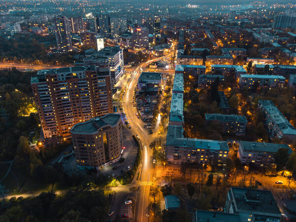 Aerial look down on city street with illumination. Blue evening Kharkiv city center. Residential district buildings and cars driving
