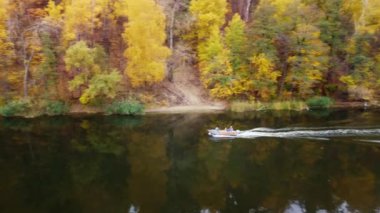 Nehirde ormanlık nehir kıyılarıyla yelken açan balıkçı teknesinin sonbahar havası manzarası. Ukrayna 'daki Siverskyi Donets Nehri