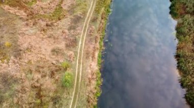 Sonbahar hava aracı toprak yol ve renkli nehir kıyılarıyla nehrin aşağısına bakıyor. Ukrayna 'daki Siverskyi Donets Nehri