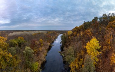Sonbahar havası nehir manzarası, sarı ağaçlar ormanı ve destansı bulutlu gökyüzü. Ukrayna 'da nehir kıyısında uçuyor.