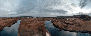 Sazlıklar ve destansı bulutlu gökyüzü ile Sonbaharda Aerial River Valley Panorama