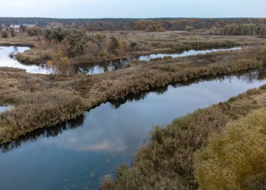 Kırsal Ukrayna 'da sonbahar nehri, ağaçlar kıyıda ve bulutlu akşam gökyüzü ile kıvrılır.