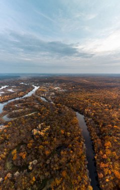 Ukrayna 'da nehir kenarlarında ormanlar ve manzaralı bulutlar olan havadan sonbahar nehri dikey manzarası
