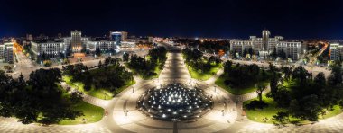 Aerial night wide panorama of illuminated fountain on Freedom Square with Karazin National University buildings in Kharkiv city, Ukraine clipart