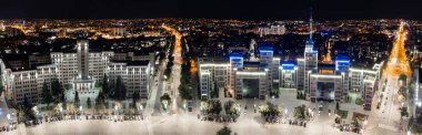 Aerial wide panorama cityscape of Derzhprom and Karazin National University buildings on Freedom Square in night illuminated Kharkiv city, Ukraine clipart