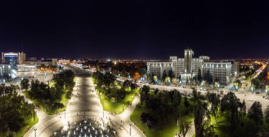 Ukrayna 'nın Kharkiv kentindeki Çeşmeli ve aydınlatılmış Karazin Üniversitesi binalı Hava Gecesi Özgürlük Meydanı manzarası