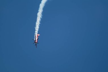 Küçük kırmızı uçak Su-31 'de hava gösterisi sırasında mavi gökyüzünde duman var.