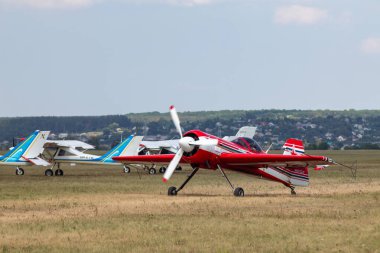 Kharkiv, Ukraine - August 29, 2021: Light red aircraft plane Su-31 landing after aerobatics on runway grass airfield at KharkivAviaFest clipart