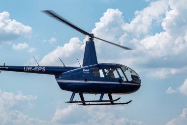 Kharkiv, Ukrayna - 29 Ağustos 2021: Mavi Helikopter Robinson R44 Raven 1 KharkivAviaFest hava gösterisinde mavi gökyüzünde bulutlarla uçuyor