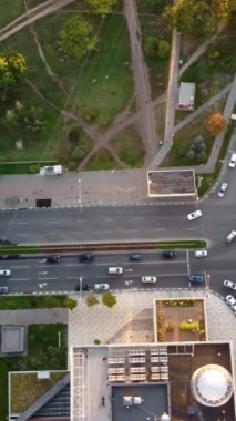 Sıcak ışıkta yeşil şehir caddelerinin kesiştiği yerde yoğun trafiğin dikey görüntüsünü takip edin.