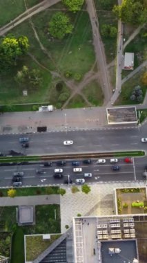 Akşam ışığında yeşil şehir caddelerinde yol ayrımında giden arabalara dikey bakış açısı