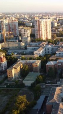 Günbatımında Harkiv şehir binaları ve caddelerinin üzerinde geriye doğru uçan hava aracı