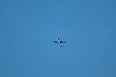 Yakovlev Yak-52, hava gösterisinde mavi gökyüzünde uçan iki koltuklu uçak.